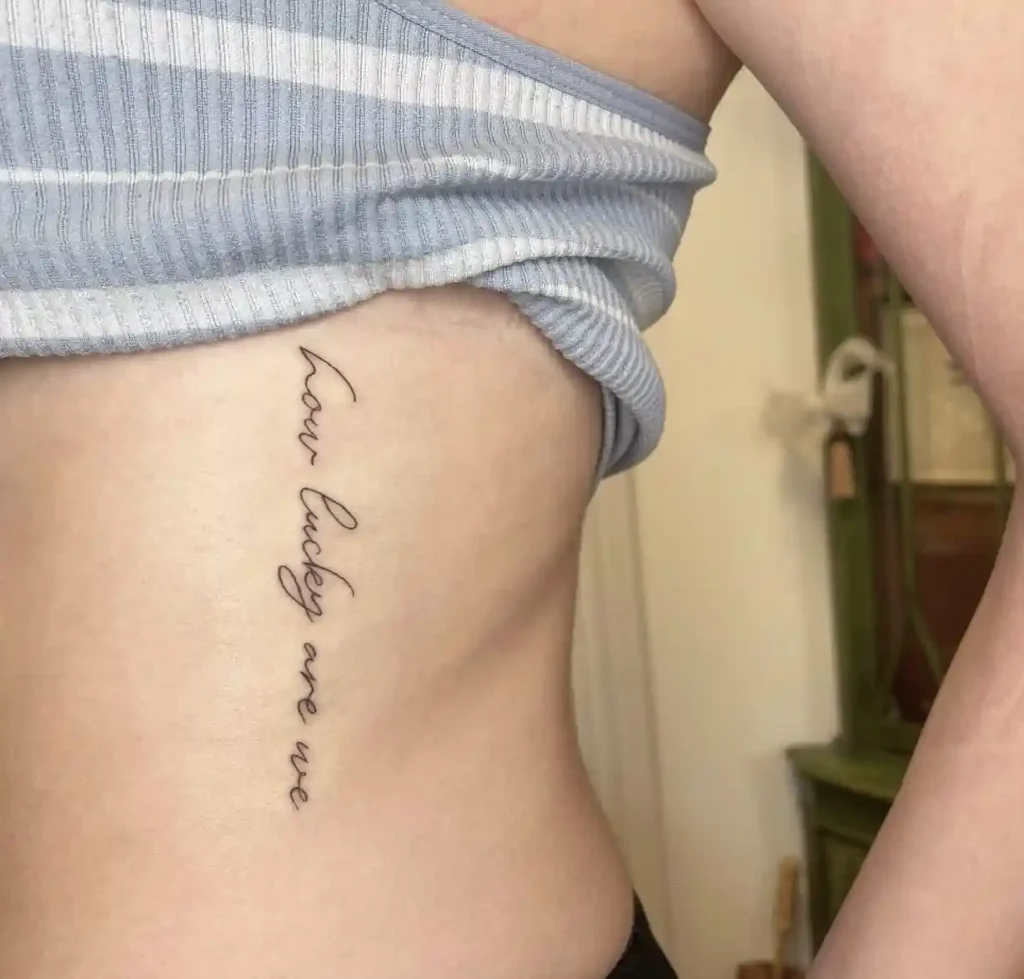 "How Lucky Are We" Vertical Ribcage Tattoo