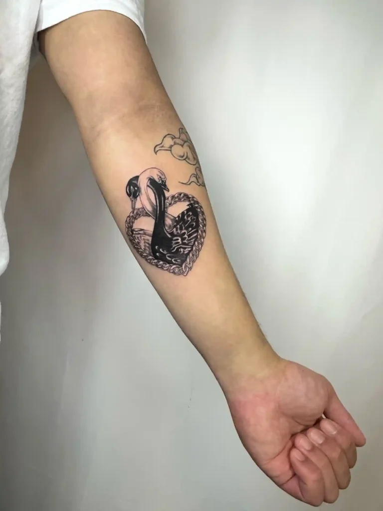 Intertwined Black and White Swans on Forearm