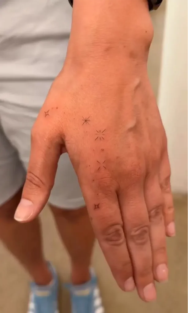 Hand Holding Spark & Starburst Tattoo