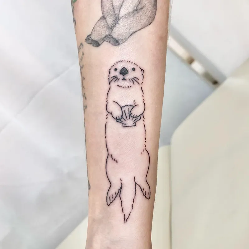 Minimalist Seashell Holding Otter Tattoo